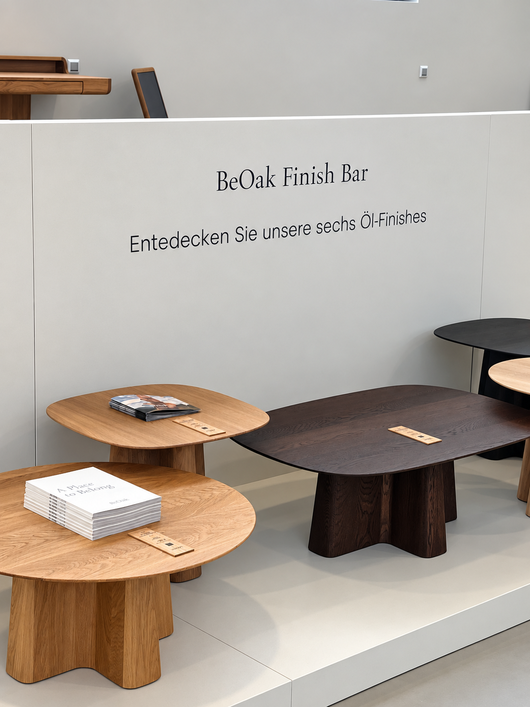 Gestapelte BeOak Kataloge und das Buch „A Place to Belong“ auf Eichentischen im Showroom Berlin