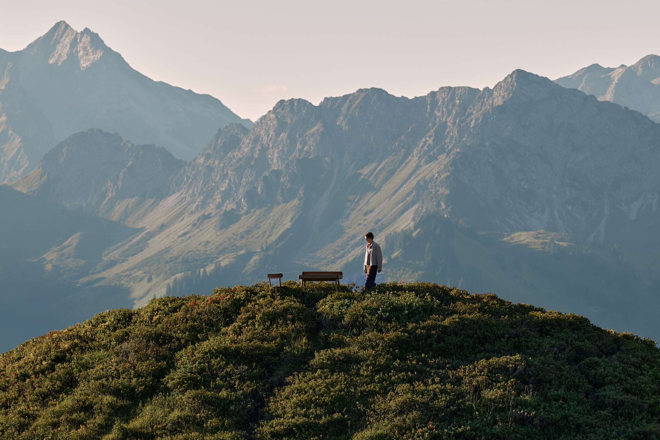 Massive Eichenbank auf einem Bergrücken vor Alpengipfeln