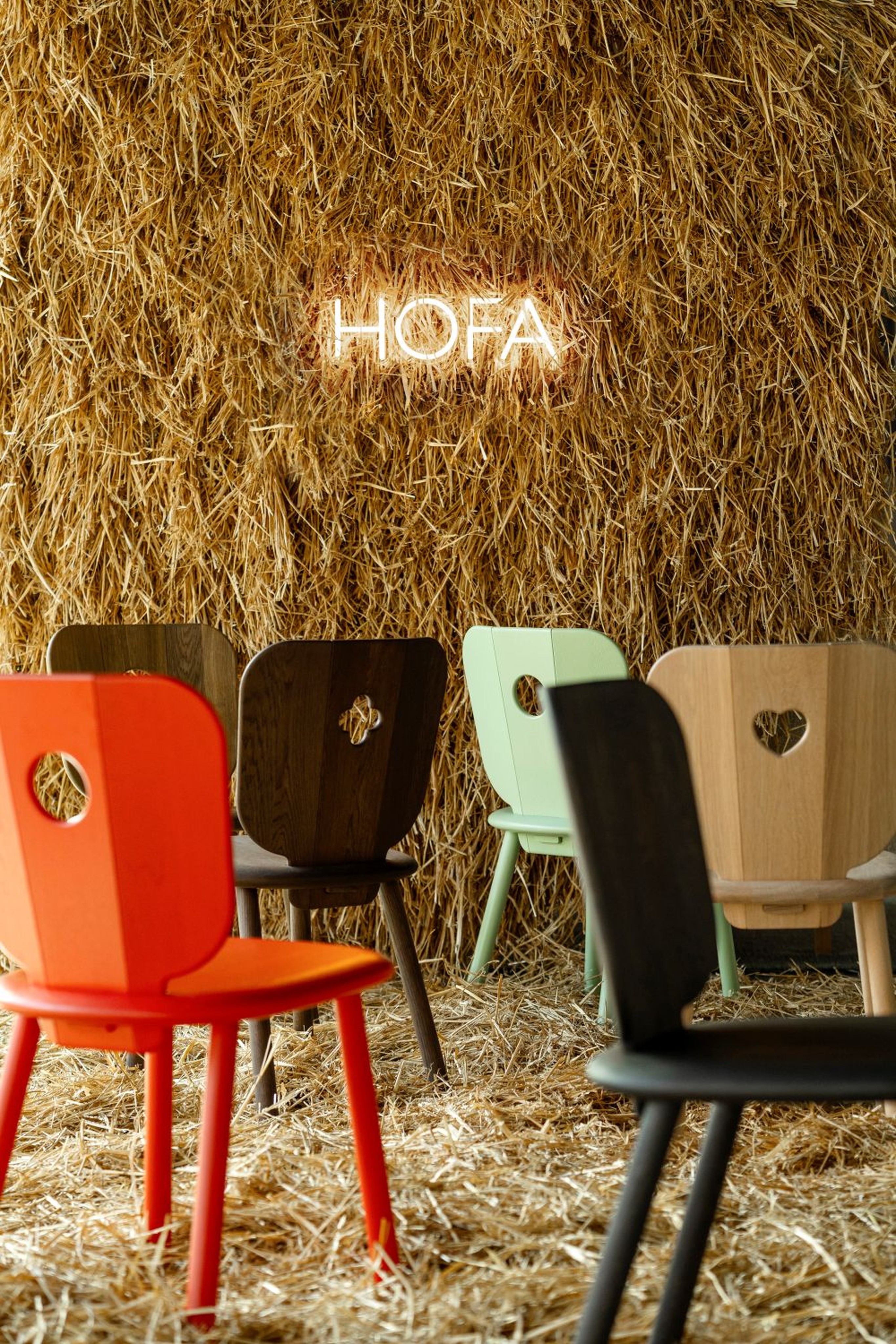 HOFA chairs in different colours in front of a straw wall